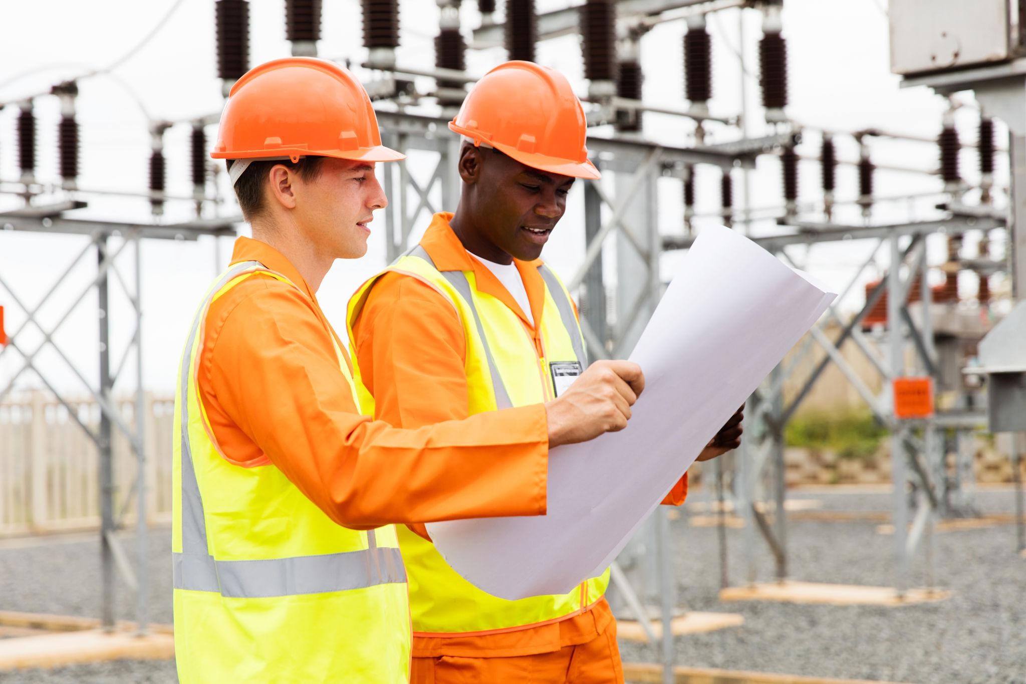 👉 "Electrical engineers designing a high-voltage substation layout and reviewing technical drawings"